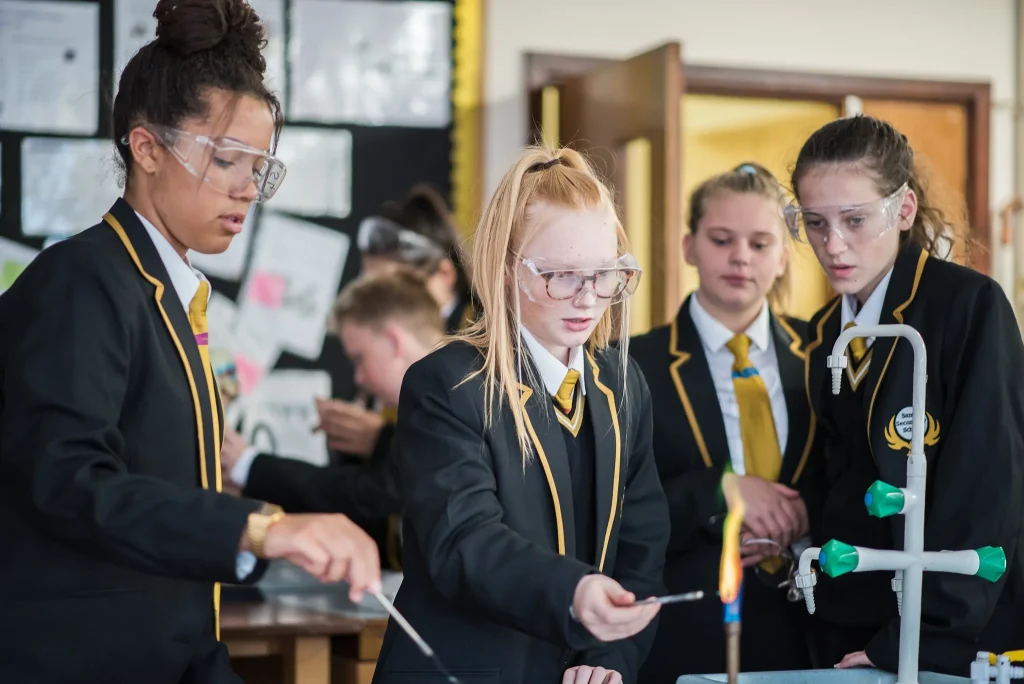 Students in safety goggles carrying out an experiment with a Bunsen burner